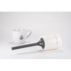 Plastové sítko na čaj i kávu v bílé barvě a v pozadí šáelk s logem Lázeňská káva