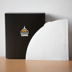 Bílý papírový filtr na dřevěném stole černá krabička s logem a bílé pozadí