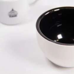 Bližší pohled na cuppingovou misku, v pozadí hrneček lázeňské kávy