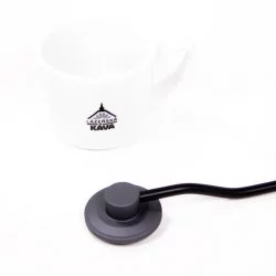 Detail na ručku ručního mlýnku Timemore na bílém pozadí s šálkem lázeňské kávy