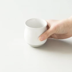 Bílý hrnek na filtrovanou kávu značky Origami Pinot Flavor v ruce.