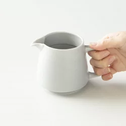 Coffee server od značky Origami v šedé barvě uchopen v rukou.