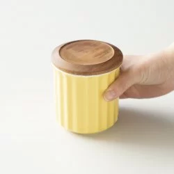Žlutá porcelánová nádoba od značky Origami v ruce.