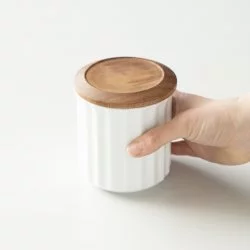 Origami porcelánová dóza na kávu v bílé barvě držena v rukou.