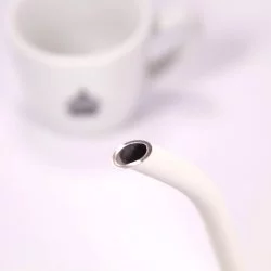 Bílá elektrická konvice, detail na hrdlo konvice, v pozadí šálek lázeňské kávy