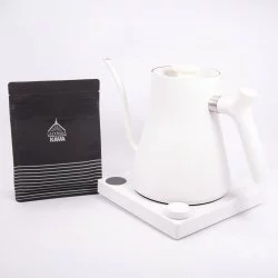Bílá elektrická konvice na bílém pozadí s balíčkem lázeňské kávy