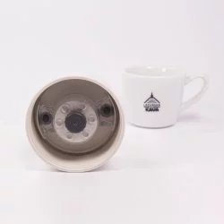 Detail víčka termosky ze spodní strany s lázeňskou kávou v pozadí.