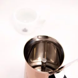 Moka konvice Bialetti New Venus pro 6 šálků na bílém pozadí s šálkem lázeňské kávy, pohled do vnitřní části konvice