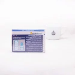 Barevná papírová krabička pro BWT Testkit tester vody a v pozadí porcelánový šálek s logem Loázeňské kávy