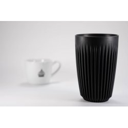 Černý ekologický kelímek Huskee o objemu 350 ml na bílém pozadí s šálkem lázeňské kávy