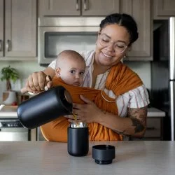 Žena s dítětem přpravující teplý nápoj do thermo hrnku značky Fellow Move c černé barvě o objemu 235ml 
