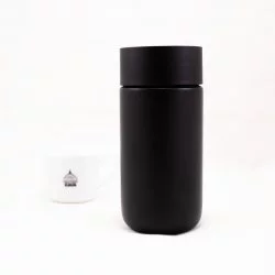 Černý termohrnek Fellow Carter s víčkem na bílém pozadí s šálkem lázeňské kávy