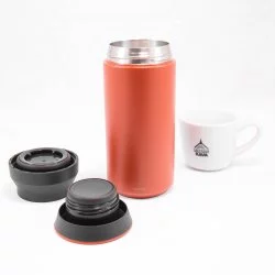 Oranžová nerezová termolahev o objemu 350 ml s rozloženým víčkem na bílém pozadí a šálkem lázeňské kávy