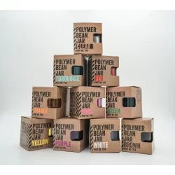 Sada barevných zásobníků na kávu v originálních krabičkách naskládaných na sobě do pyramidy na bílém pozadí
