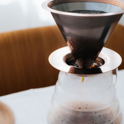 Kovový dripper Hario Pink Gold vedle konvice Kovový dripper Hario Pink Gold vedle konvice
