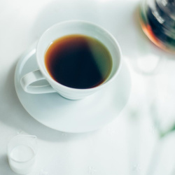 Šálek Hario V60 s kávou stojící na podšálku