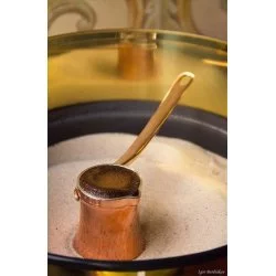 Příprava turecké kávy v pískovém vařiči v měděné džezvě 