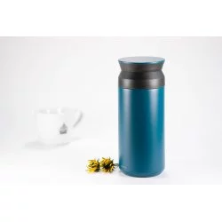 Tyrkysová nerezová termoláhev o objemu 350 ml na bílém pozadí s šálkem lázeňské kávy a květinami