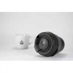 Plastový thermo hrnek tmavé barvy s šedým držákem ležící na bílém stole s bílým hrnkem na kávu značky Lázeňské kávy