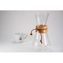 Skleněný Chemex s protáhlou hlavou dřevěnou rukojetí koženým provázkem a bílý šálek na kávu s logem