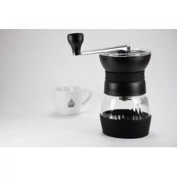 Černý ruční mlýnek Hario Skerton Pro s šálkem lázeňské kávy v pozadí